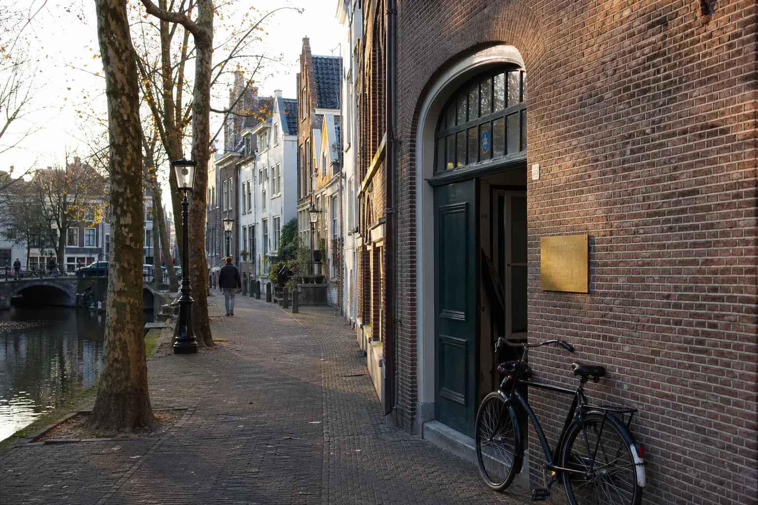 Bakstenen grachtenpand in Utrecht met groene voordeur van het Olympisch erfgoedcentrum StartStoot in laat zonlicht